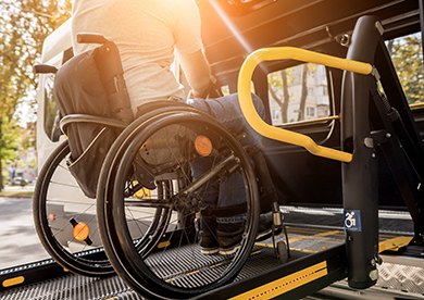 A man in a wheelchair uses a lift to enter a shuttle bus