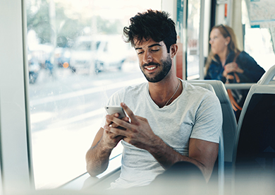 a man uses his smart phone while riding on a bus
